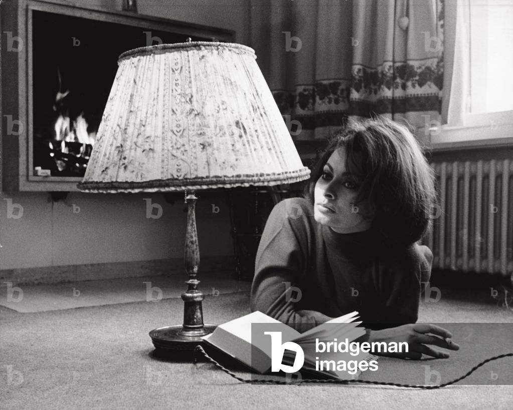 Sophia Loren is reading a book lying on the floor, 1963 (b/w photo)