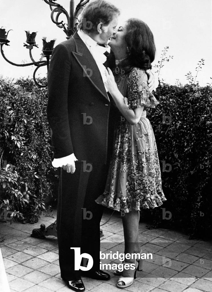 Elizabeth Taylor and Richard Burton kiss each other on a terrace