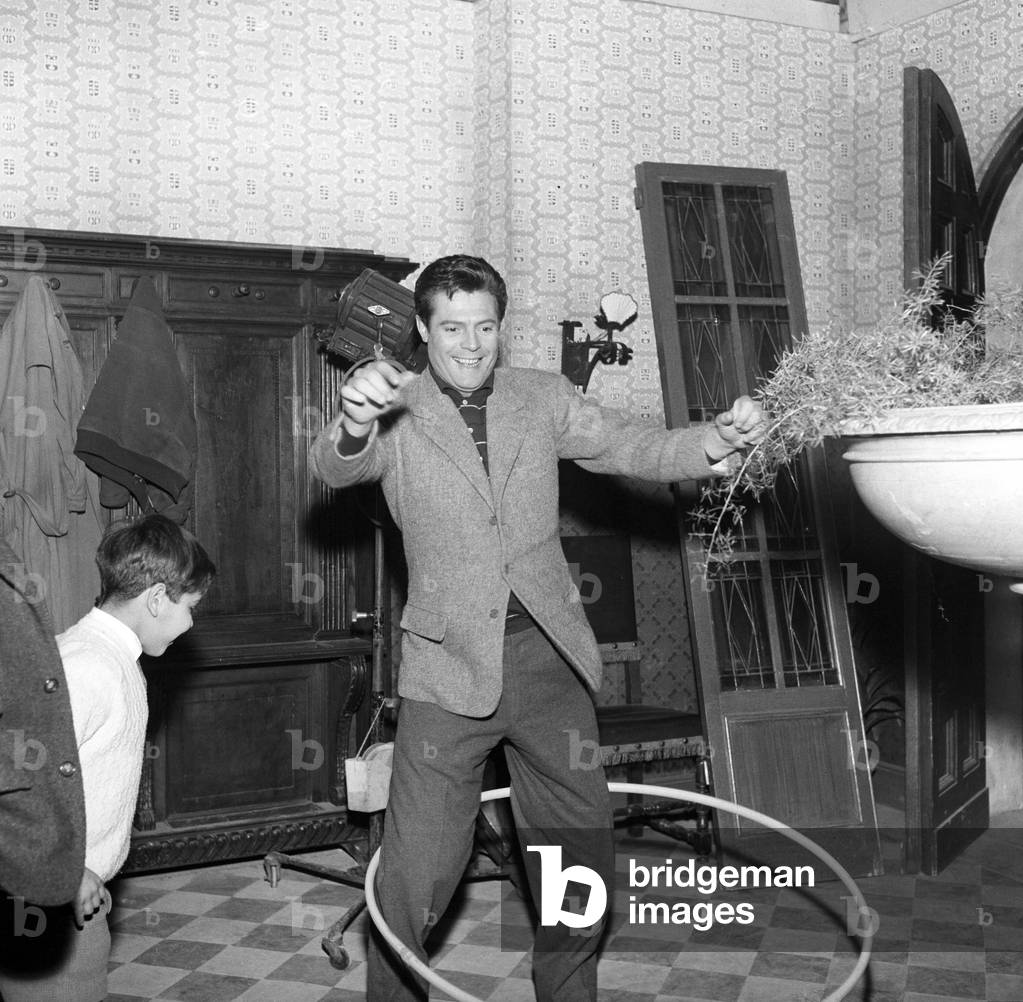 Marcello Mastroianni using a hula-hoop on the set of Everyone's in Love, Italy, 1958 (b/w photo)