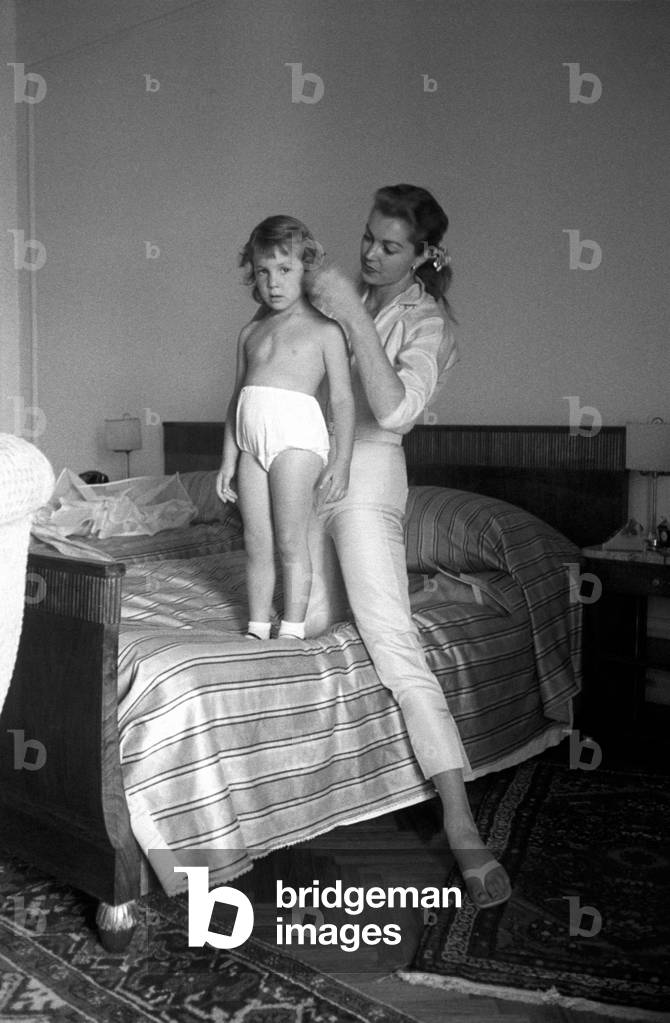 Esther Williams combs her daughter's hair on the bed