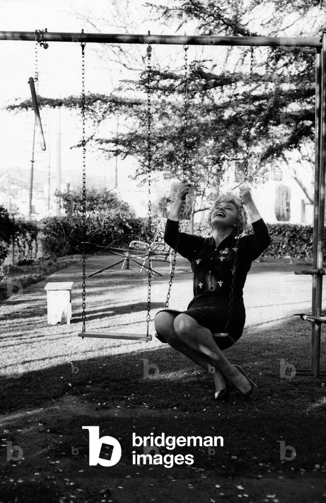 Shelley Winters on the swings in the garden of her house