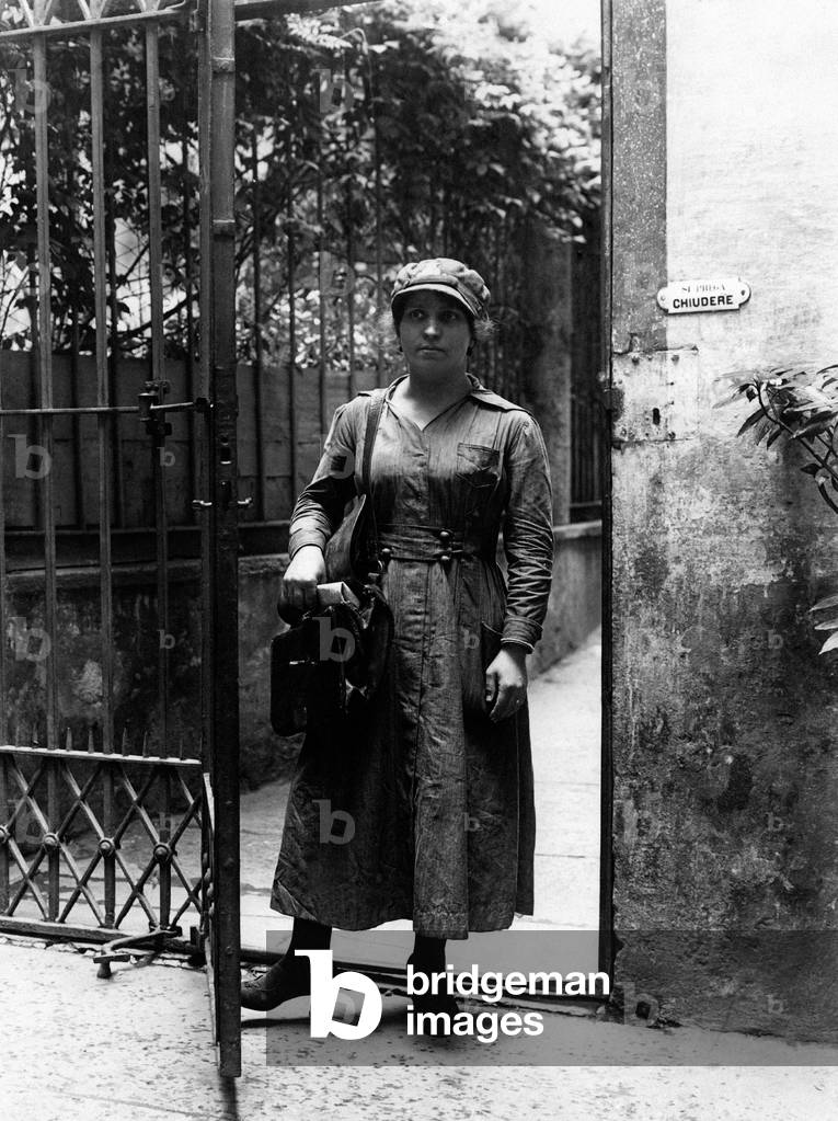 A postwoman posing in the doorway of a house
