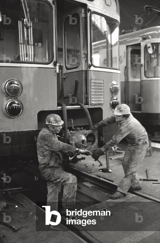 Two workers are repairing a buffer of an underground coach