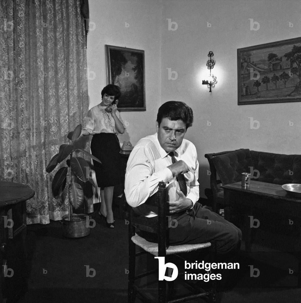 A husband worried because his wife is chatting on the phone, Italy