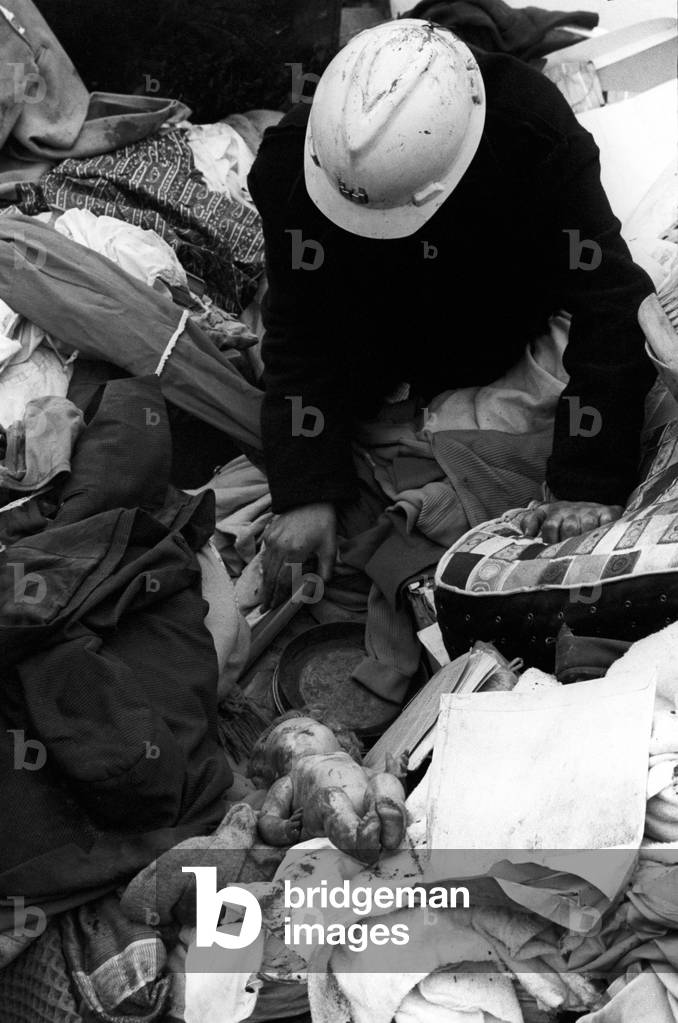 A man with his helmet leaning over clothes and objects, Aberfan, Great Britain