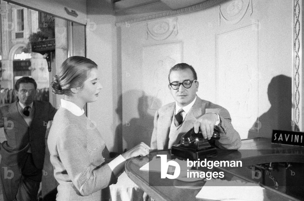 The actress Jacqueline Sassard watches the director Antonio Pietrangeli handling a telephone at a bar counter during a break from the shooting of the movie 