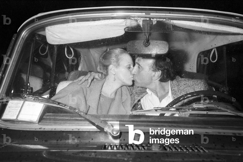Italian TV host Pippo Baudo with Katia Ricciarelli in a car, Italy, 1983 (b/w photo)