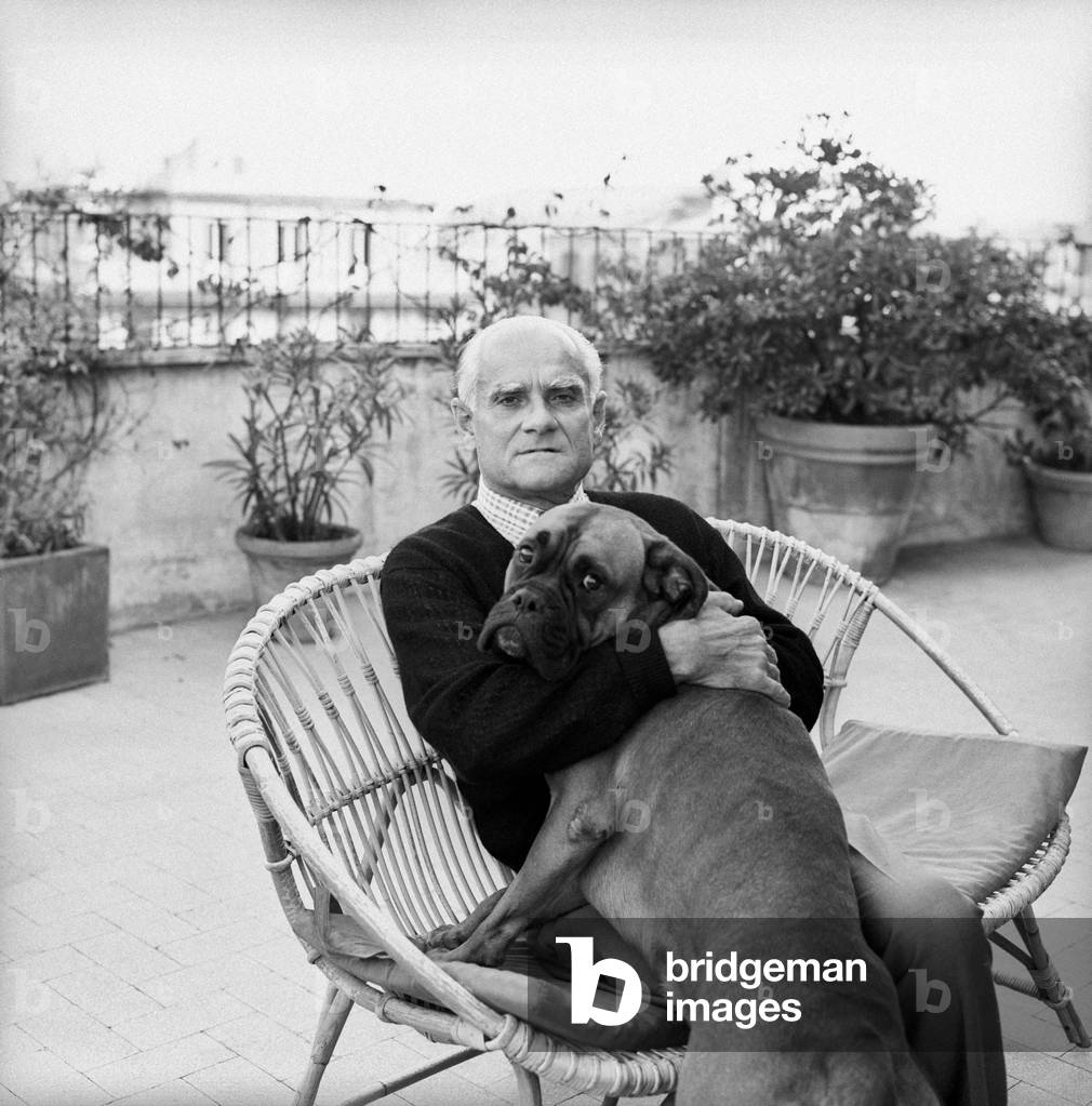 Alberto Moravia hugging a dog, Italy, 1960