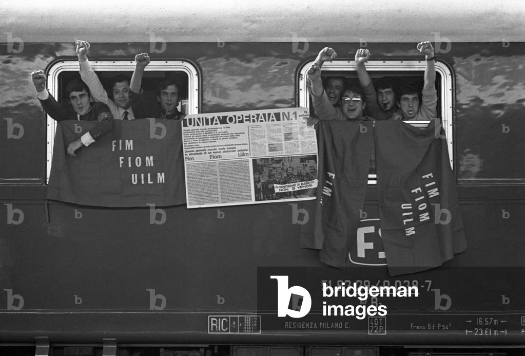 Workers on a train showing the raised fist during a metalworkers' demonstration, Turin, 1969 (b/w photo)