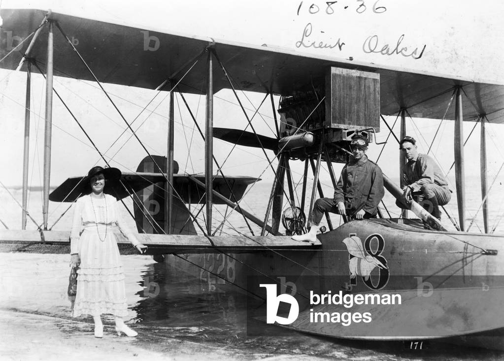 A woman poses by a beached seaplane at Dinner Key, c.1918 (b/w photo)