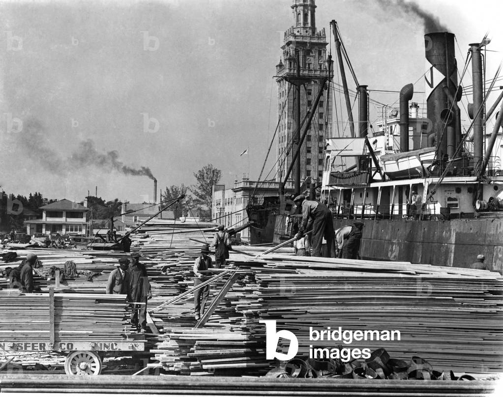 African American workers stack lumber at the Port of Miami, 1925 (b/w photo)