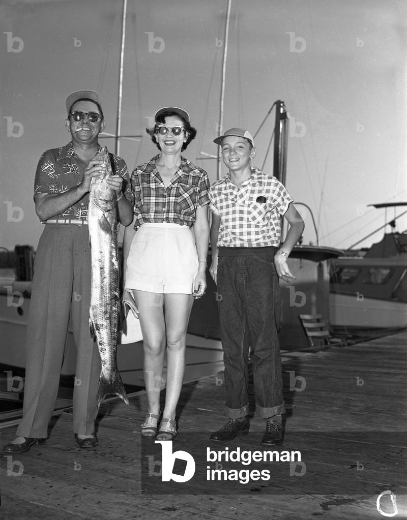 A family shows off their catch from a deep sea fishing trip, 1950 (b/w photo)
