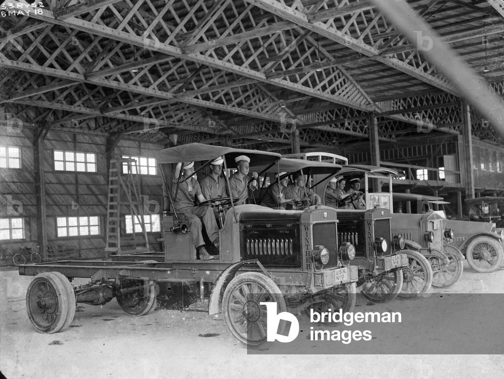 Navy men in flatbed trucks inside a hangar at the U. S. Naval Air Station at Dinner Key, Florida, 1918 (b/w photo)