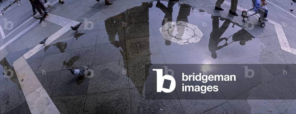 Venice. St. Mark's square, the bell tower reflected in a puddle