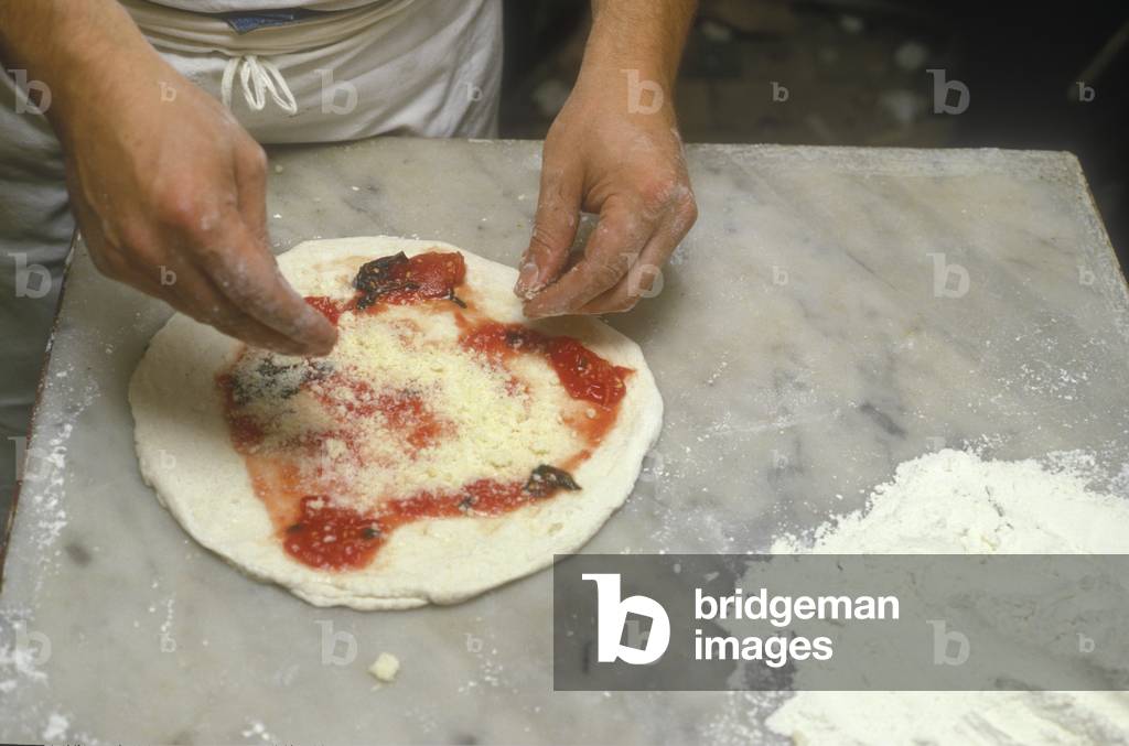 Naples, Italy. Preparation of Pizza Margherita at Brandi pizza restaurant, where in 1889 it was invented in honour of Queen Margaret (Margherita) of Savoy. Fourth step: sprinkle with grated Parmesan cheese