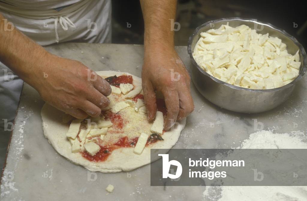 Naples, Italy. Preparation of Pizza Margherita at Brandi pizza restaurant, where in 1889 it was invented in honour of Queen Margaret (Margherita) of Savoy. Fifth step: sprinkle with Mozzarella cheese