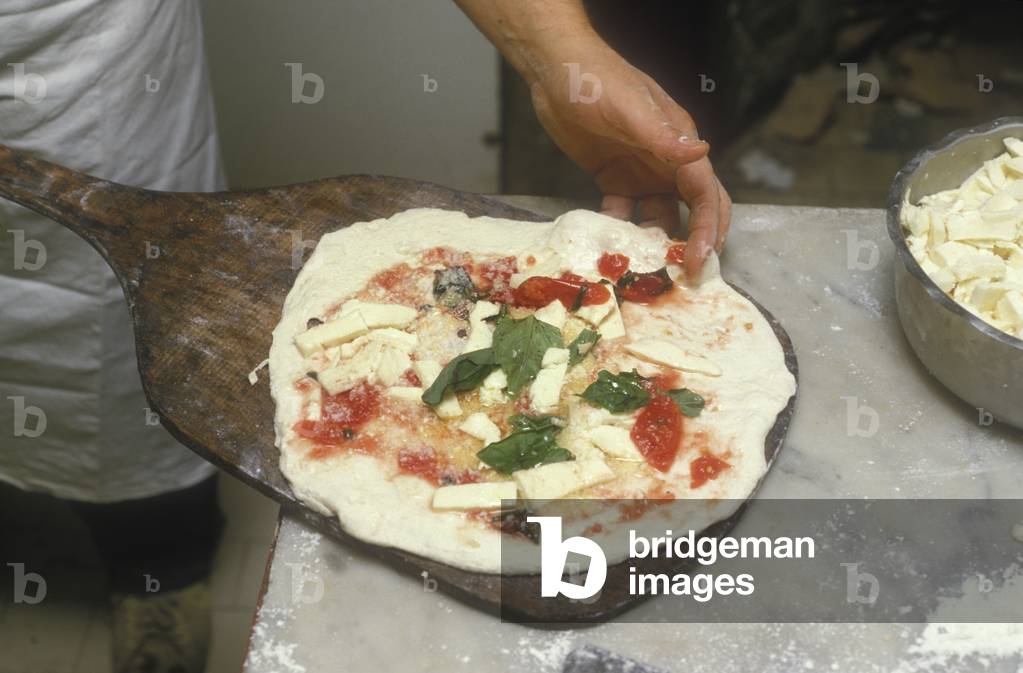 Naples, Italy. Preparation of Pizza Margherita at Brandi pizza restaurant, where in 1889 it was invented in honour of Queen Margaret (Margherita) of Savoy. Seventh step: pizza is ready to be put in the oven