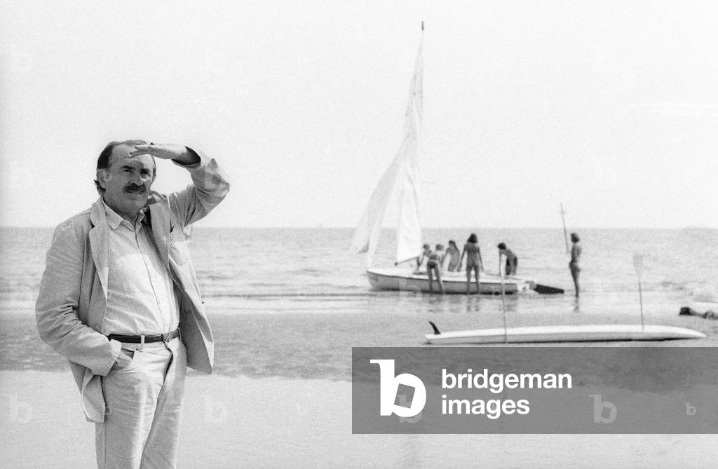 Venice Film Festival 1983. Italian poet and scriptwriter Tonino Guerra walking on the Lido Beach/Mostra del Cinema di Venezia 1983. Tonino Guerra, poeta e sceneggiatore, mentre passeggia sulla spiaggia del Lido -