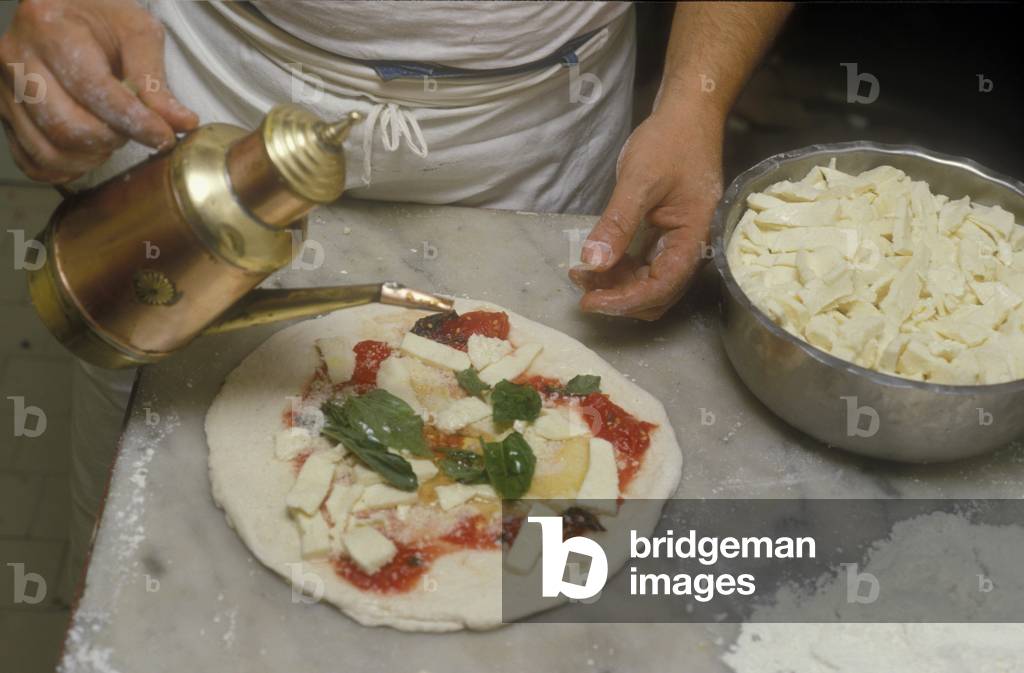 Naples, Italy. Preparation of Pizza Margherita at Brandi pizza restaurant, where in 1889 it was invented in honour of Queen Margaret (Margherita) of Savoy. Sixth step: add a little olive oil