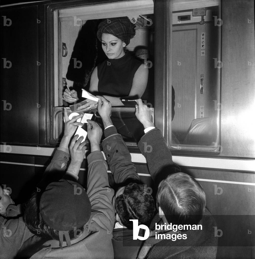 Rome, Termini Railway Station, about 1965. Italian actress Sophia Loren while signing autographs from a train window/Roma, 1965 circa. L'attrice Sophia Loren mentre firma autografi dal finestrino di un treno -