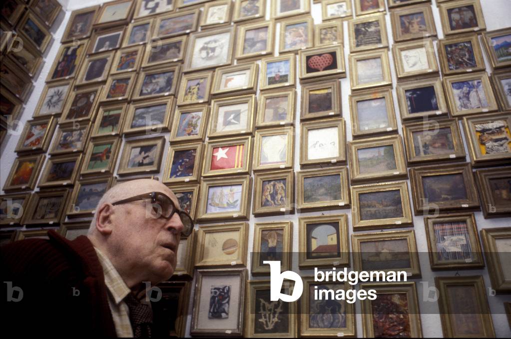 Portrait of writer and painter Cesare Zavattini posing near his collection of miniatures in 1979.