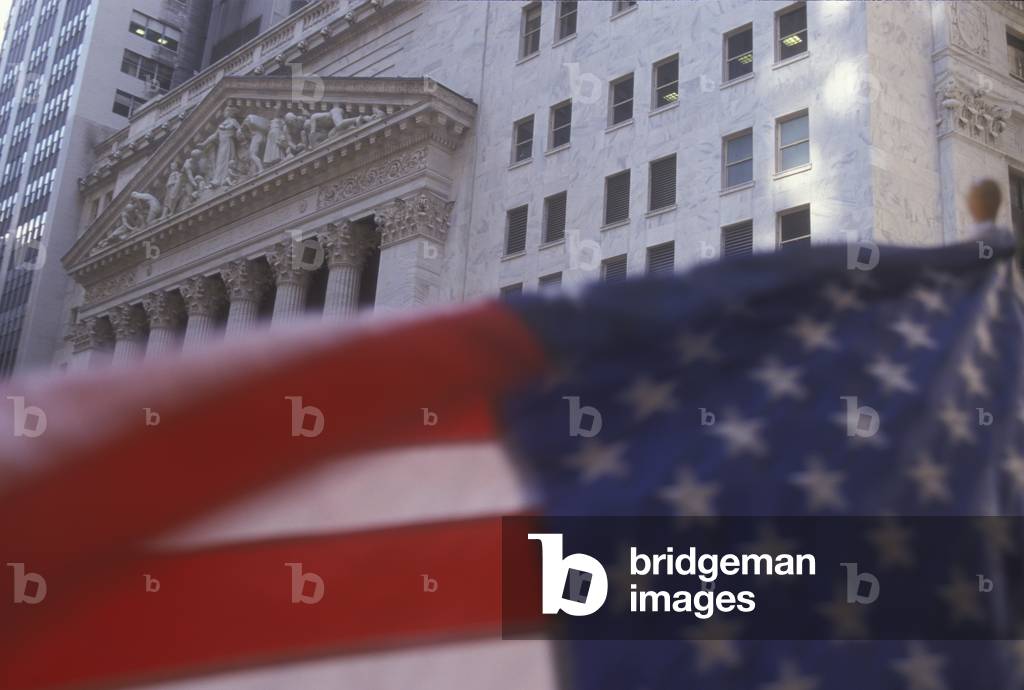 New York Stock exchange in Wall Street with American flag in foreground (2000)