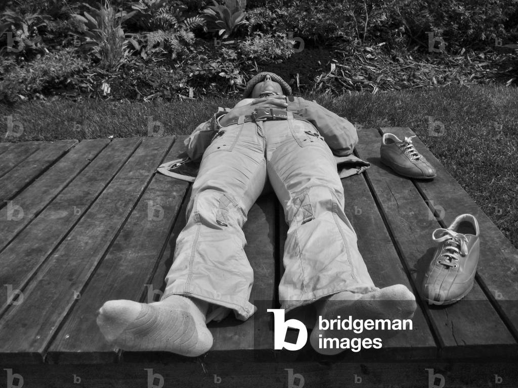 Man lying in the sun at the Hotel de Ville (City Hall) garden in Paris