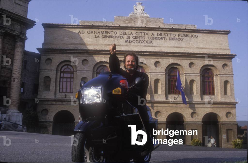 Macerata, 1992, Austrian director Gustav Kuhn on motorbike in front of the Sferisterio/1992. Il direttore d'orchestra Gustav Kuhn in moto davanti allo Sferisterio-