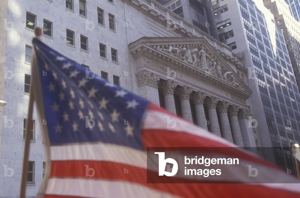 New York Stock exchange in Wall Street with American flag in foreground (2000)