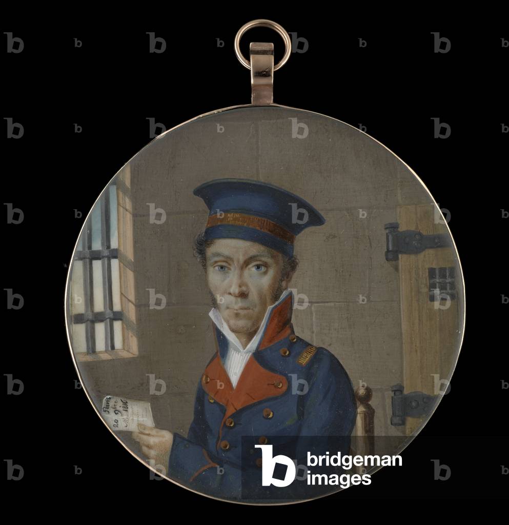 Portrait miniature of an Officer, wearing dark blue uniform with red collar and lapels, his dark blue hat with gold braid, seated in a prison cell, a letter in his left hand inscribed ‘Paris/ 20 9bre/ 1816’ (w/c on ivory)
