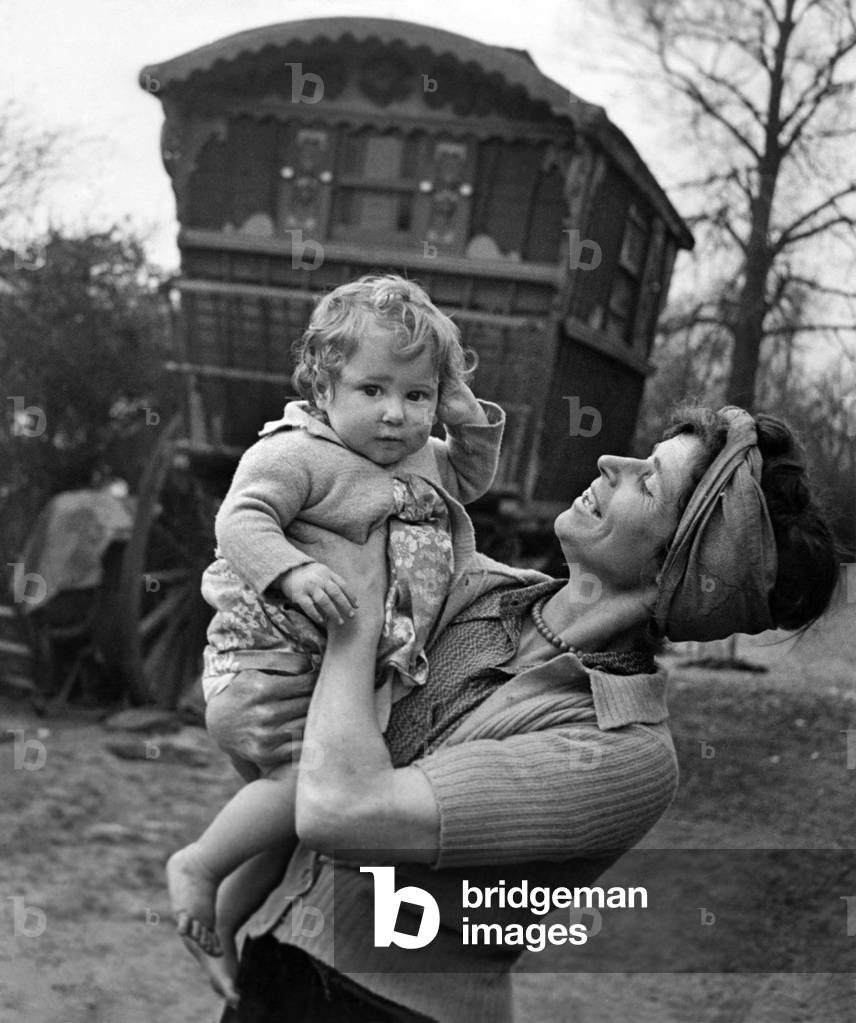 Gypsy woman with child pose outside their caravan. July 1944