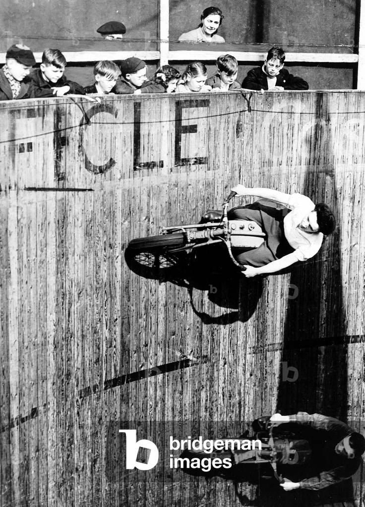 Margy Dare passes her colleague dare devil Jake during their Fly on the ceiling act at Morecombe in the Wall of Death, 23/04/1947 (b/w photo)
