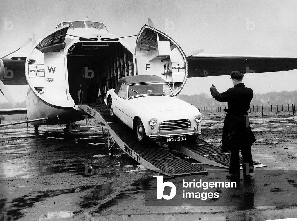 The Bristol Type 170 Freighter was designed with the unique feature of opening nose doors, which made it eminently suitable as a cargo aircraft. It was not long before Silver City Airways were attracted to the idea of starting cross-channel services for cars between England and France. Its first flight was at Filton, Bristol on 2 December 1945 following which a total of 241 of all marks were eventually constructed. Pictured is a Swallow Dorretti sports car being loaded into a Silver City Airways aircraft, most likely from their base of Ferryfield in Kent., c. 1955 (b/w photo)
