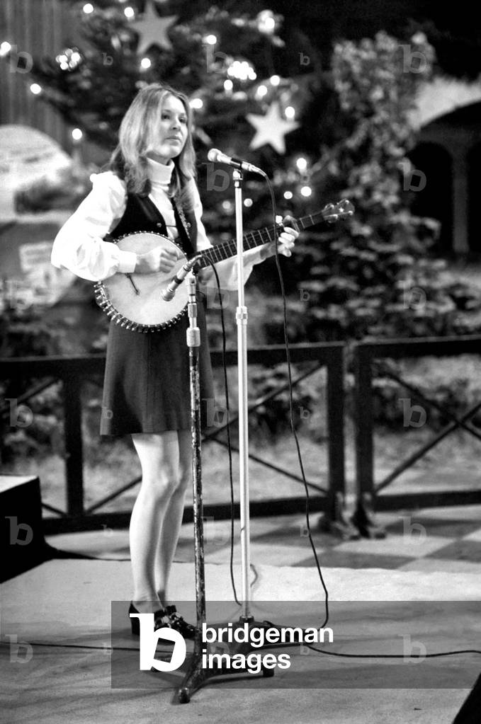 Folk singer Suzanne Harris sings to a lunch time audience in St. Pauls Cathedral. The tree behind her was one of those presented to St. Pauls by the Queen. 
December 1969