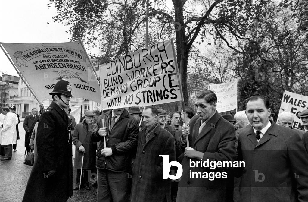 Hundreds of blind workers today staged a protest in Belgrave Square, London, for better wages. They want an increase of £1.5. a week on the £14.5s. Basic pay of 3,500 blind workers. At No. 41, Belgrave Square, a meeting was being held to discuss their wage claims. The Blind workers with their placards during the protest in Belgrave Square. November 1969