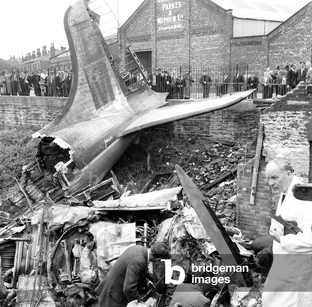 Board of Trade investigators and Rolls Royce experts at work, site of Stockport Air Disaster, the crash of a Canadair C-4 Argonaut aircraft owned by British Midland Airways, registration G-ALHG, near the centre of Stockport, Greater Manchester, England on Sunday 4 June 1967. 72 of the 84 aboard were killed in the accident. Of the 12 survivors, all were seriously injured. Tail of plane and sightseers at the site of the crash, 5th June 1967 (b/w photo)