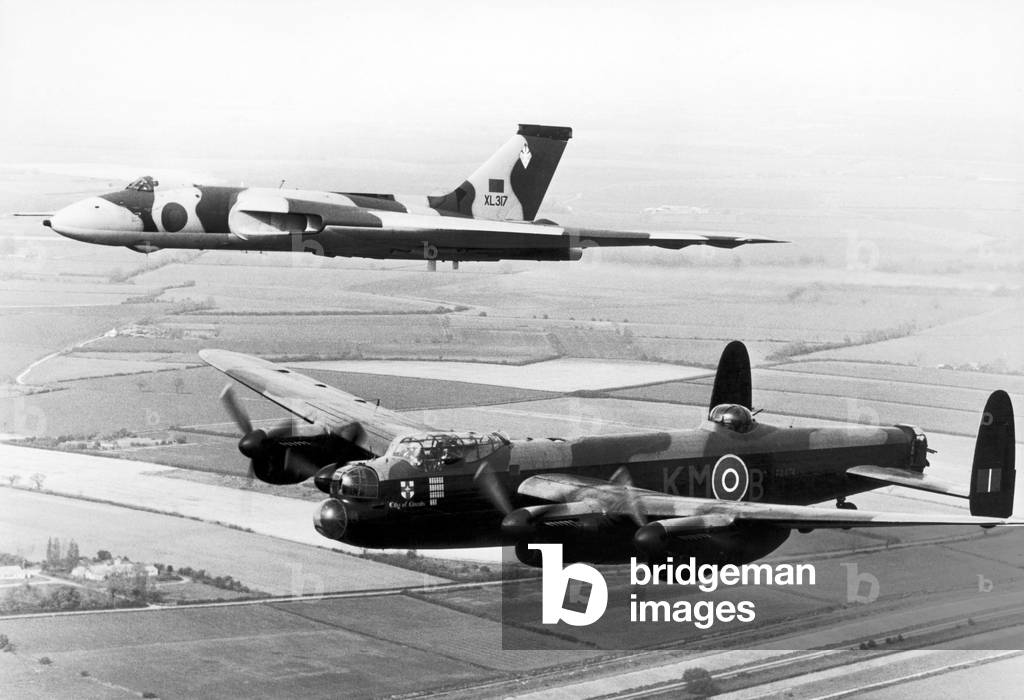 Avro Lancaster bomber commemorative flight over Derwent Dam, seen here escorted by an Avro Vulcan during the Coventry air display at Baginton. August 1977 (b/w photo)