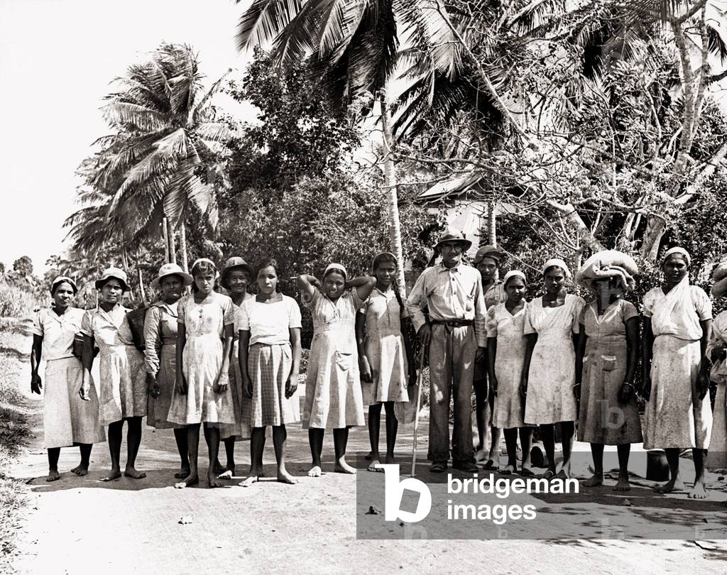 Trinidad West Indies sugar workers including children in the Woodford lodge estate under gang driver Lal Mohamed holding stick, c.1940 (b/w photo)