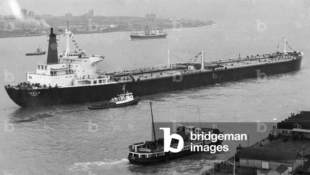 Thousands of Merseysiders had never seen anything like her. The big ship that sailed into their river as they lined the waterfront. The 206,000-ton tanker Melo is seen on her slow but sure manoeuvre into the Tranmere oil terminal at Birkenhead-across the water is Liverpool. February 1969 (b/w photo)