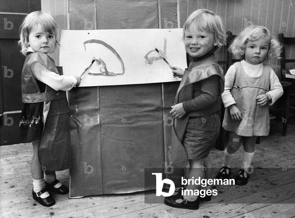 Budding artitsts Vicky Hutchinson, Richard Gibson and Venetia Charlton enjoy a painting lesson at nursery school, 22nd September 1972 (b/w photo)