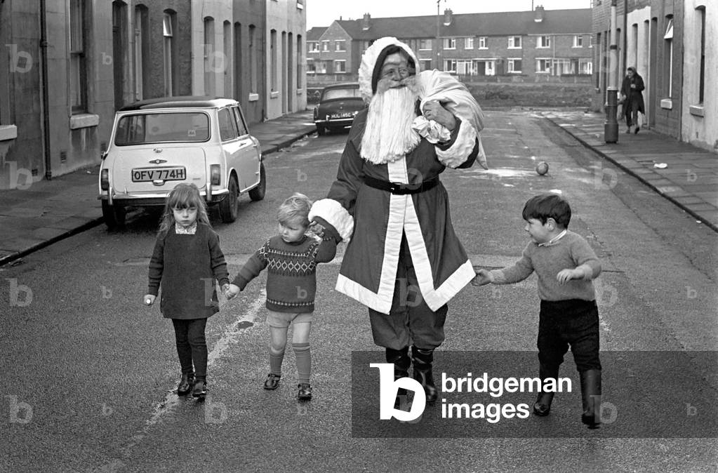 An elderly woman dressed as Santa Claus on her way to an engagement accompanied by neighbourhood children, December 1969
