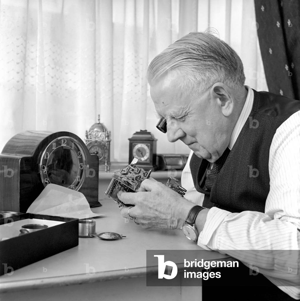 Timelord: Clock repairer Bill Marshall seen here repairing the movement to a mantle clock. 1960