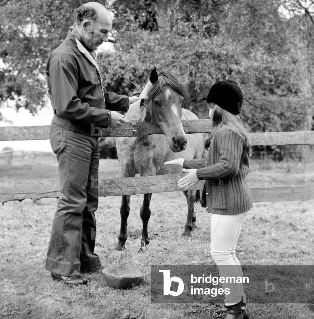 Sterling Moss (Ex Racing Driver). Seen here with horse and daughter. June 1974