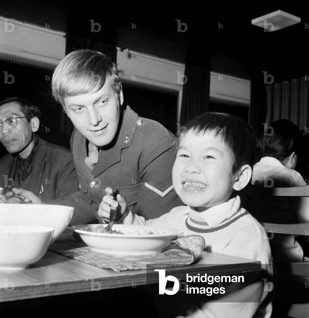 Vietnamese child eating his dinner in the canteen at a haven for child victims of the Vietnam war in Peaceville, West Germany.