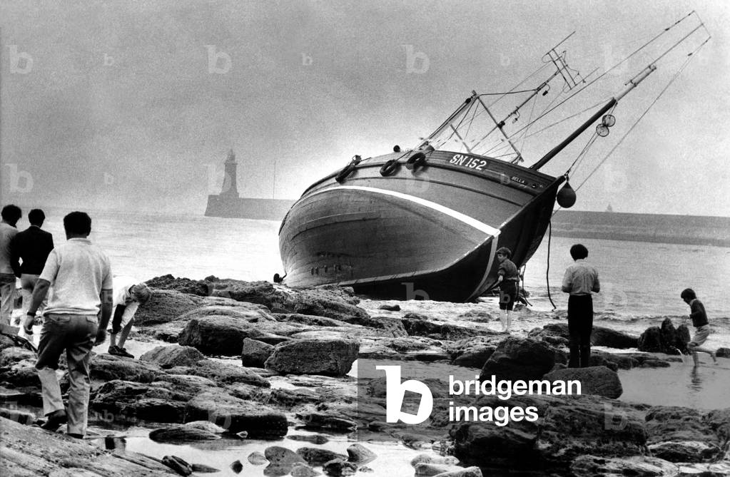 North East Shipwrecks - The seine-net fishing boat Bella pictured on the rocks 50 yards from the shore at Tynemouth. The boat ran aground the previous night in thick fog and was badly holed. The five crew escaped by lifeboat. 17th July, 1972 (b/w photo)