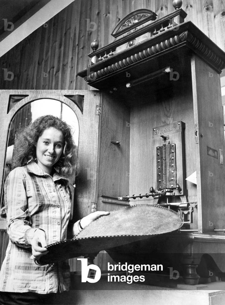 A young girl changes the disc on a vintage juke box or polyphone in September 1972 04/09/1972 (b/w photo)