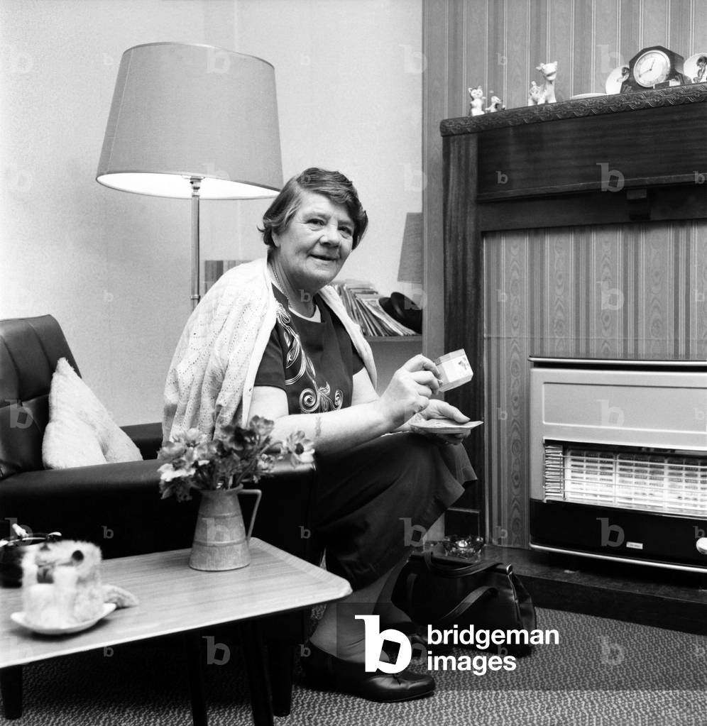 British family feature: Old woman sitting by the fireplace in her living room
November 1969
