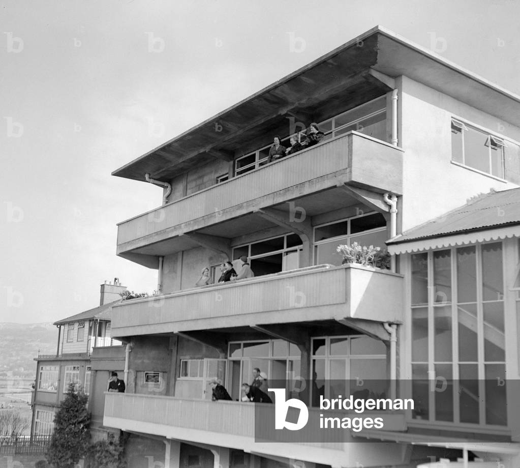Queen Elizabeth the Queen Mother at Cheltenham racecourse in 1956 watching the racing from a balcony in the main stand. 8th March 1956 (b/w photo)