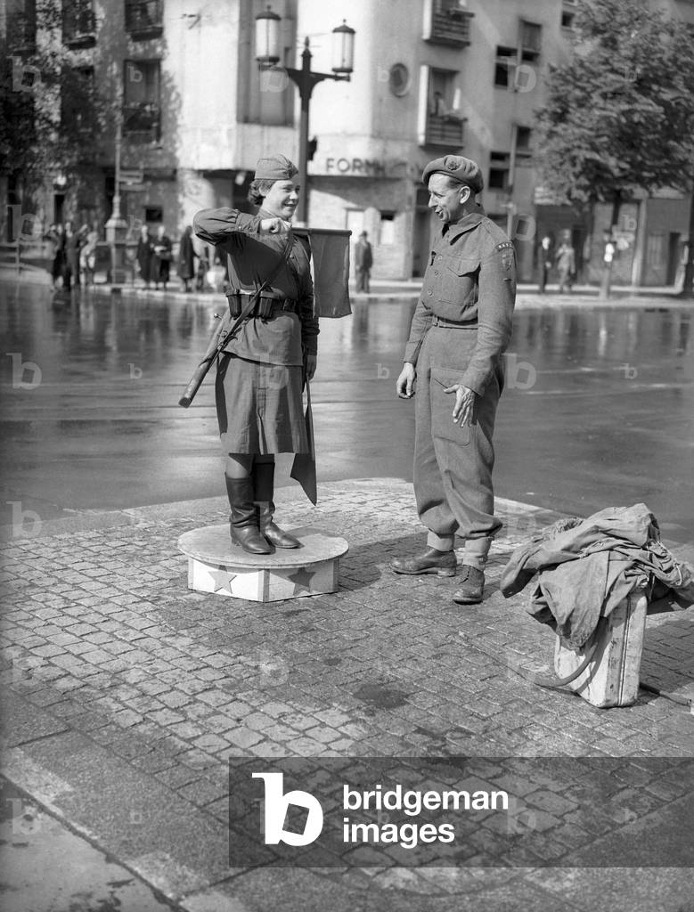 A spot of fraternising between a Russian army girl on traffic duty and a British Tommy soldier in the Unter den Linden in occupied Berlin after World War Two July 1945 (b/w photo)