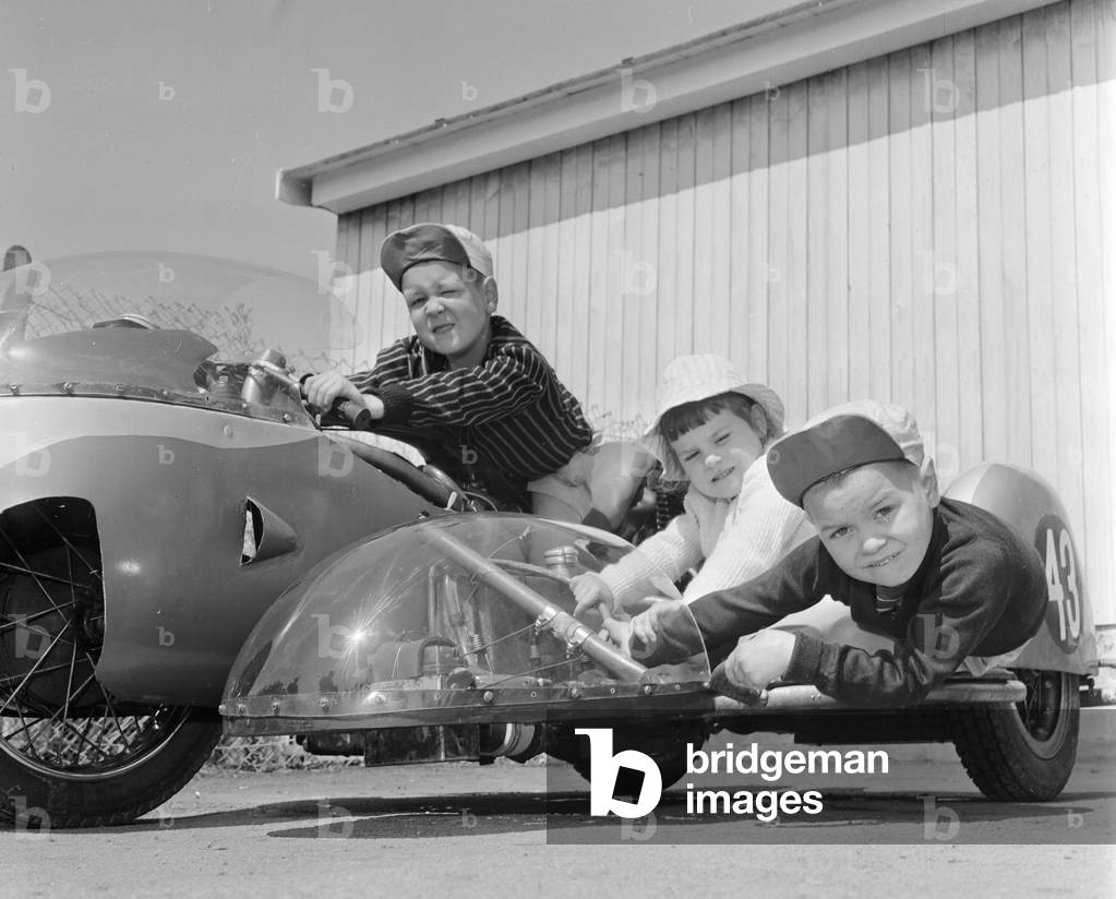 Three children Brian, Carole Ann and Colin Digby sitting on their dad's 498cc Triumph sidecar, 29th June 1965 (b/w photo)